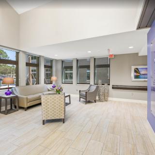 A modern living room with ample natural light streaming through large windows, featuring comfortable seating and stylish decor.