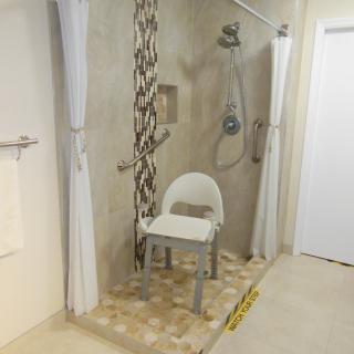 An accessible shower with a shower chair and safety grab bars.