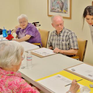 A group of seniors participates in an art class, each working on their own painting project.