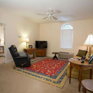 A cozy living room with a sofa, TV, and colorful rug.