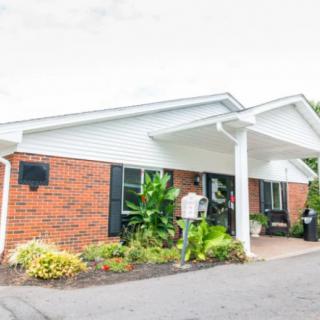 A brick building with a landscaped entrance and covered porch.