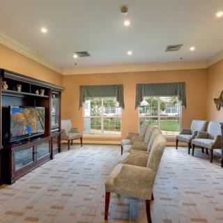 A comfortable waiting room with neatly arranged chairs, a television, and large windows.