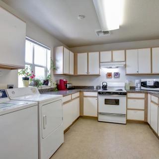 A spacious kitchen with white cabinets, appliances, and a laundry area.