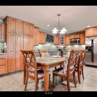 A spacious kitchen with wooden cabinetry, a dining table set, and modern stainless steel appliances.