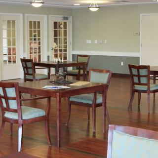 An empty dining room with wooden tables and chairs set on a polished wood floor.