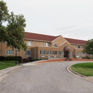 A charming residential building with a red roof and landscaped surroundings.