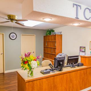 A welcoming reception area with a wooden desk, computer, and fresh flowers.
