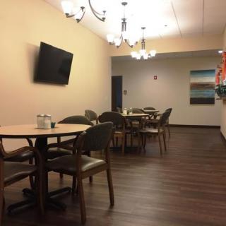 A cozy dining area with a modern design, featuring wooden floors and a wall-mounted television.