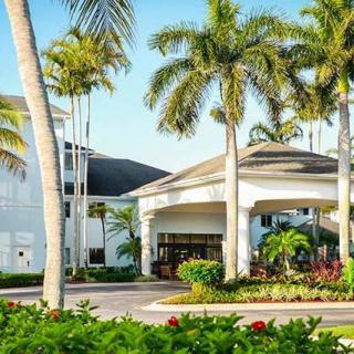 A tropical hotel entrance surrounded by palm trees and lush landscaping.