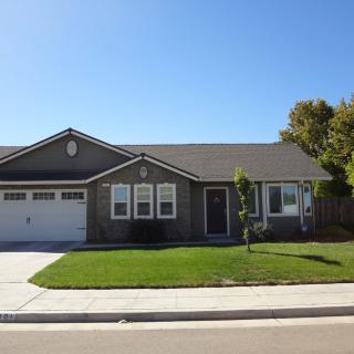 A single-story suburban house with a neatly maintained lawn and attached garage on a sunny day.