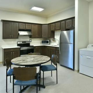 A modern kitchen and dining area with dark brown cabinets, stainless steel appliances, and a round table with chairs.