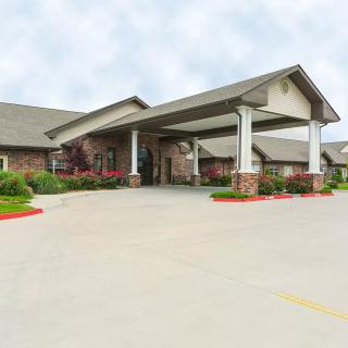 A wide view of a building's main entrance featuring a covered walkway, surrounded by well-maintained landscaping.