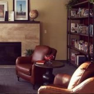 A cozy living room with leather armchairs, a fireplace, and a well-stocked bookshelf.