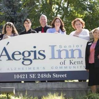 A group of people standing in front of the Aegis Inn of Kent sign.