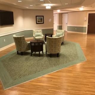 A cozy seating area with four chairs around a table on a carpeted section of the floor in a hallway.