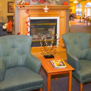 A cozy living room with two armchairs, a small table, and a fireplace.
