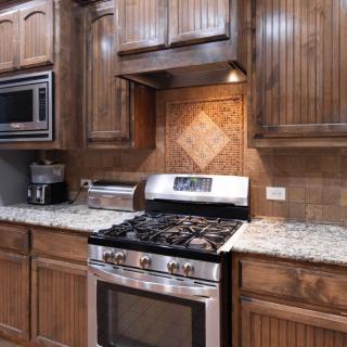 A modern kitchen with wooden cabinets, a granite countertop, and stainless steel appliances.