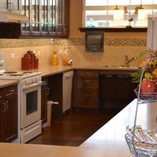 A cozy kitchen featuring a stove, countertops, and wooden cabinets with decorative touches.