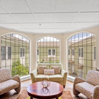 A bright and cozy living room with large arched windows, featuring comfortable seating and a round wooden table.