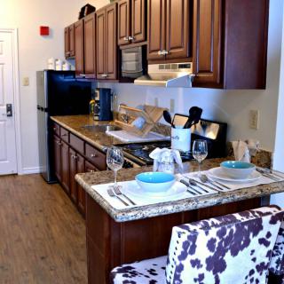 A modern kitchen and dining area featuring a granite countertop with bar seating, wood cabinetry, and stylish decor.