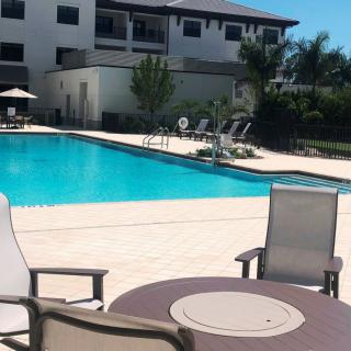 A sunny day at a residential swimming pool with lounge chairs and apartment buildings in the background.