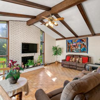 A cozy living room featuring exposed wooden beams, a brick fireplace, and comfortable seating.