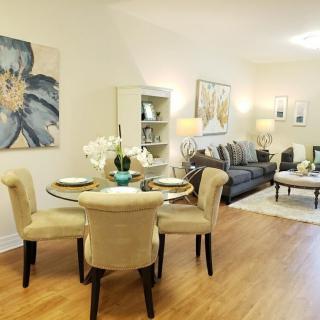 A modern and cozy living room with a dining area, featuring comfortable seating, elegant furniture, and decorative artwork on the walls.
