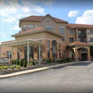 A modern residential building with a covered entrance and landscaped driveway.