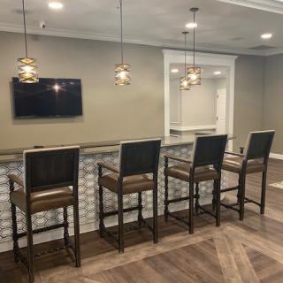 A modern bar area with high chairs, a counter, and a mounted television.
