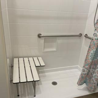 Accessible shower with a bench and grab bars.