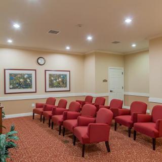 A neatly arranged waiting or conference room with red chairs and decorative paintings.