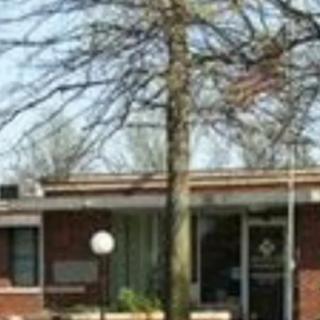 A brick building with a tree and a flagpole in front.