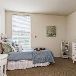 A cozy and well-decorated bedroom featuring blue bedding, white walls, and stylish furnishings.