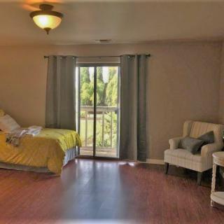 A cozy bedroom with a bed, chair, and sliding glass door letting in natural light.