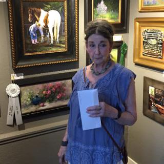 A woman stands in an art gallery surrounded by various paintings, holding a piece of paper.