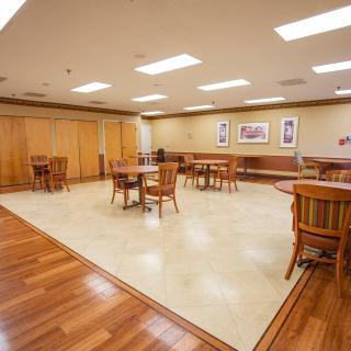 Spacious conference room with wooden flooring and multiple seating arrangements.
