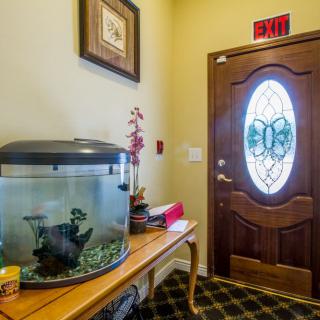 A cozy entryway with a fish tank on a wooden table next to an ornate front door.