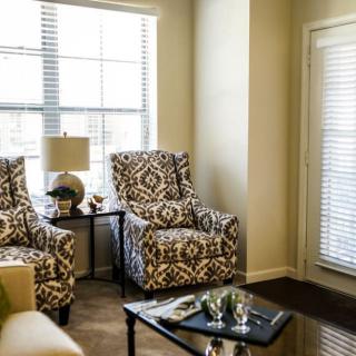 A cozy living room with patterned chairs and a coffee table next to large windows.