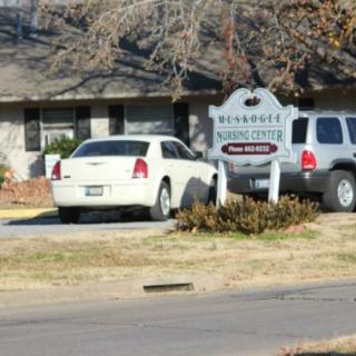 Two cars parked in a driveway in front of a building with a sign.