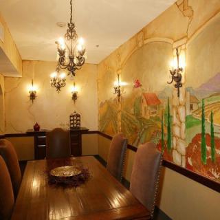 A warmly lit dining room with a mural on the wall and a chandelier overhead.
