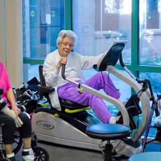 Elderly individuals engaging in fitness activities on stationary bikes indoors.