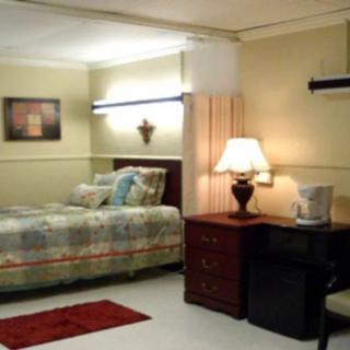 A cozy bedroom with a neatly made bed, side table, and lamp.