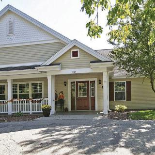 A charming residential house with a spacious porch and surrounding trees.