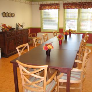 A well-arranged dining room with a long wooden table and chairs, decorated with vases of flowers.