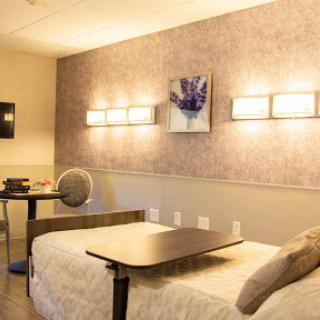 A well-lit patient room featuring a comfortable bed, a side table, and calming decor.
