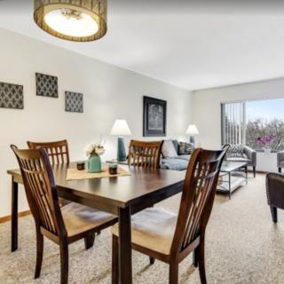 A well-furnished dining and living area with a wooden table and chairs, sofa, and decorative elements.
