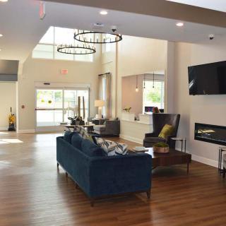 A modern lobby interior with seating, a chandelier, and a fireplace.
