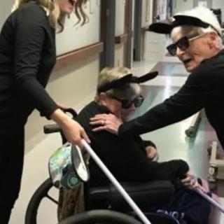 People in costumes having fun in a hallway with someone in a wheelchair.
