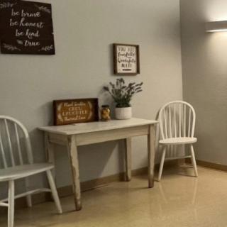 A cozy interior setting featuring a small table flanked by two chairs, adorned with decorative wall art and a potted plant.