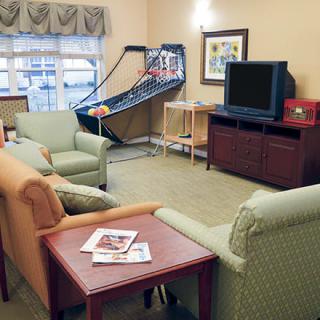 A cozy living room with seating, a television, and an arcade basketball game.